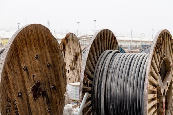 Close-up of large wooden reels holding industrial cables in an outdoor supply yard.